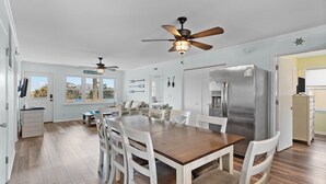 A spacious kitchen with a large island, white cabinetry, and a stainless steel refrigerator.