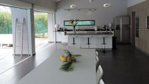 Een moderne keuken met een centraal eiland, een koelkast en een eethoek met een tafel voor twee personen.