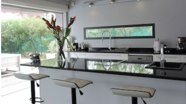 Een moderne keuken met een groot schiereiland, barstoelen en een flatscreen televisie.