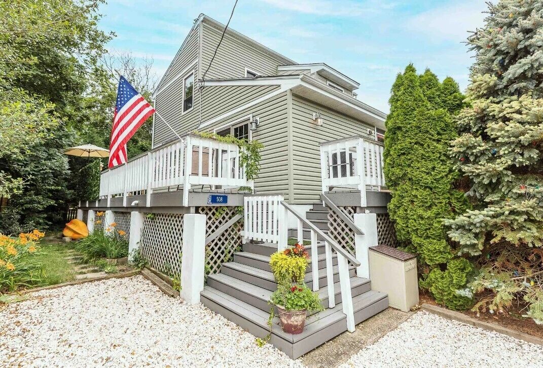 Une maison à deux étages avec un porche, un drapeau et une plaque portant le numéro 508.