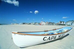 A lifeboat named "CAPE MAY" on a sandy beach with buildings in the background. - Water Views - 3 Min Walk to Private Beach - Luxury 5-Star Rated Beach House (Lower Township)