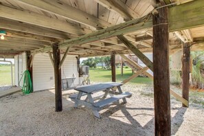 An outdoor covered area with a picnic table, wooden beams, and a green hose.