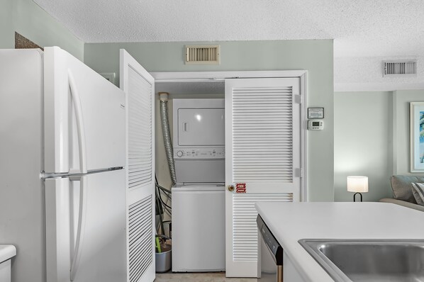 A compact kitchen with a refrigerator, washing machine, and a sink.
