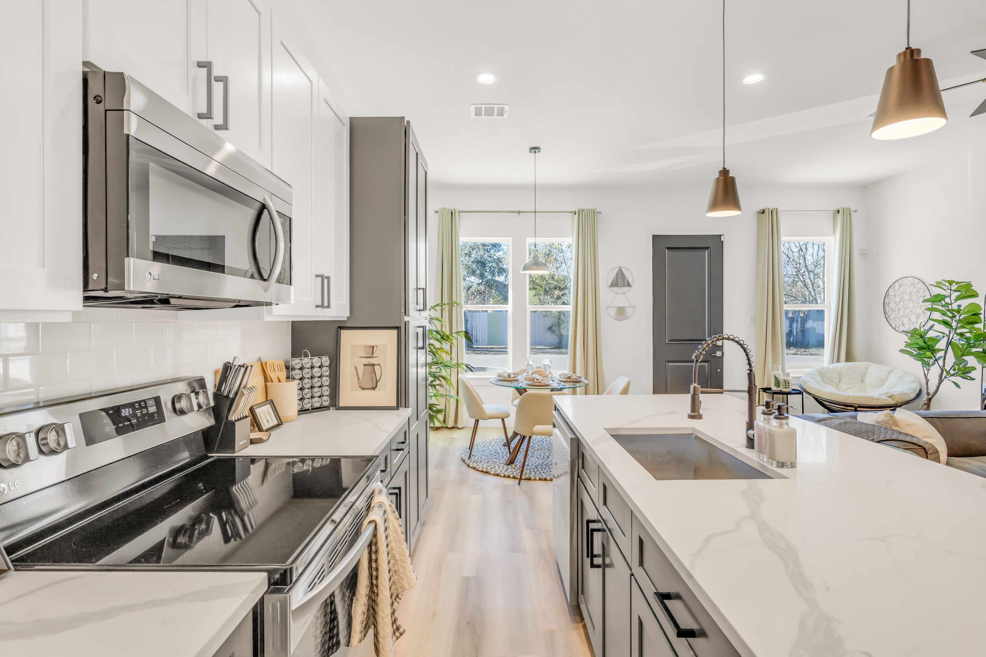 A modern kitchen with stainless steel appliances, a central island, and a dining area with a view.