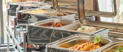 Un buffet proposant une variété de plats et des plateaux de service en métal.