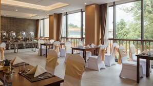 A spacious dining area with high ceilings, large windows, and a view of the outdoors. Tables are set with white chairs and napkins. - White Swan Guest House Meizhou (Meizhou)