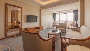 A hotel room with a living area featuring a sofa, chairs, a coffee table, a TV, and a balcony with a view. - White Swan Guest House Meizhou (Meizhou)