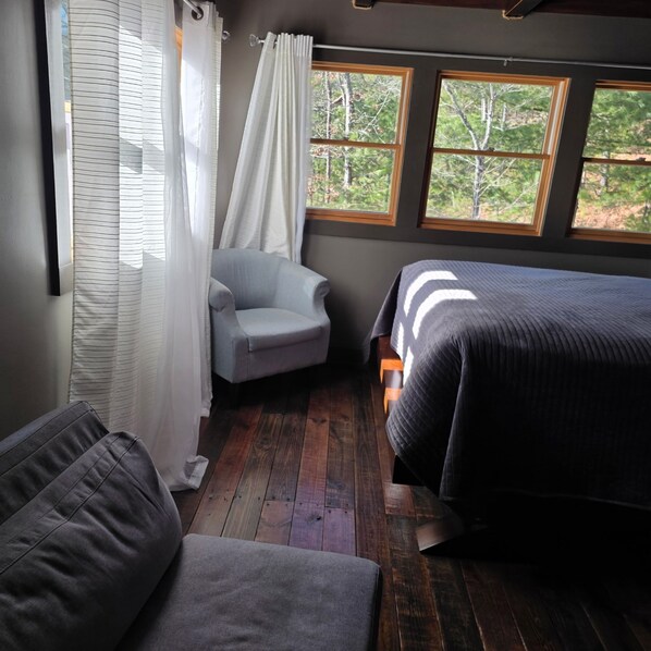 A bedroom with two beds, a chair, and a window with a view of trees. - Cozy cabin in Hot Springs, minutes away from town! (Hot Springs)
