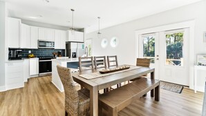 Una cocina moderna con armarios blancos, una mesa de comedor de madera y un horno empotrado.