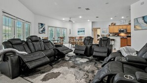 Een ruime woonkamer met leren fauteuils, een eethoek en een keuken.