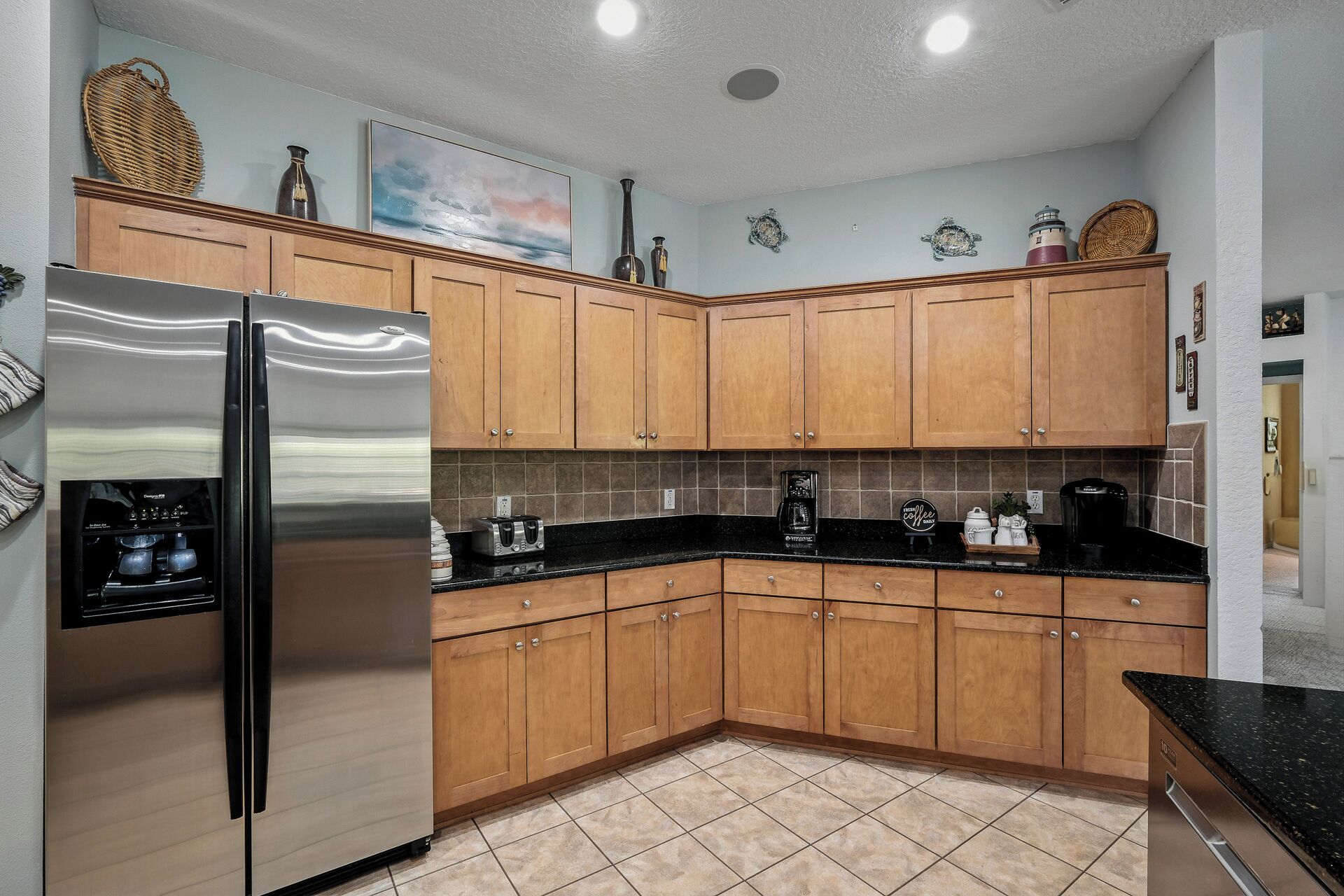 A kitchen with wooden cabinets, a stainless steel refrigerator, a coffee maker, and a toaster.