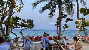 Ein Essbereich im Freien mit Tischen und Stühlen, Fisch und Meeresfrüchte auf Tabletts angerichtet, und Blick auf das Meer.