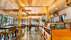 Ein geräumiges Restaurant mit Holzbalkendecke, großen Fenstern und einem glänzenden Boden.