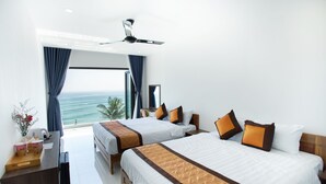 Ein Hotelzimmer mit zwei Betten, einem Schreibtisch und Blick auf das Meer.