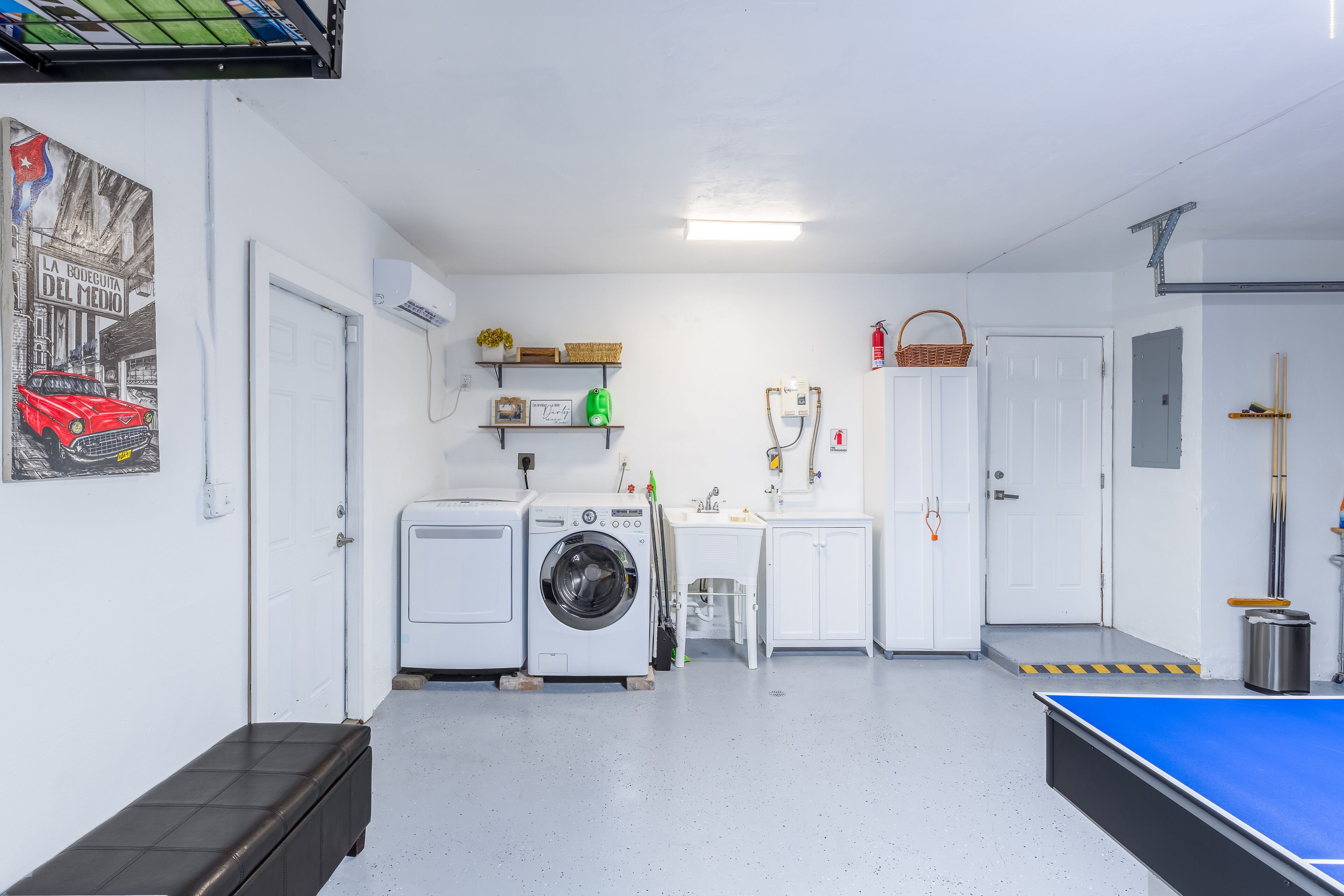 Un lavadero con lavadora, secadora, lavabo y una mesa de ping pong.