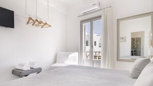 Ein modernes Schlafzimmer mit einem großen Bett, einem Flachbildfernseher, einem Kleiderschrank mit Holzaufhängern und einem großen Spiegel.