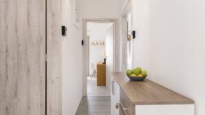 Ein Flur mit einer Holztür, einer Wandleuchte und einer Obstschale auf einer Anrichte.
