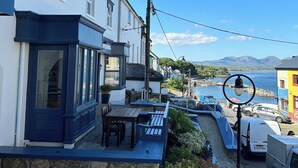 Um hotel à beira-mar com fachada de pedra, área de estar ao ar livre e vista para o mar.