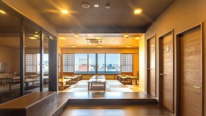 A modern interior with a long corridor, wooden benches, and large windows offering a city view. - Cogo Ryogoku (Tokyo)