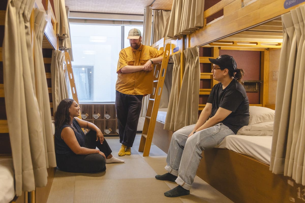 Une chambre avec un lit superposé, une échelle, une fenêtre et des rideaux.