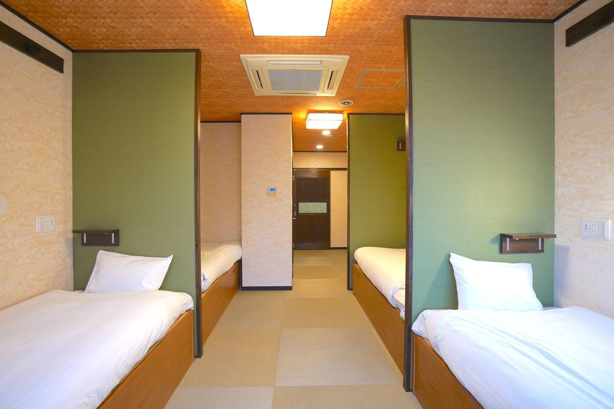 Une chambre d’hôtel avec deux lits simples, un plafond en bois et un mur vert.