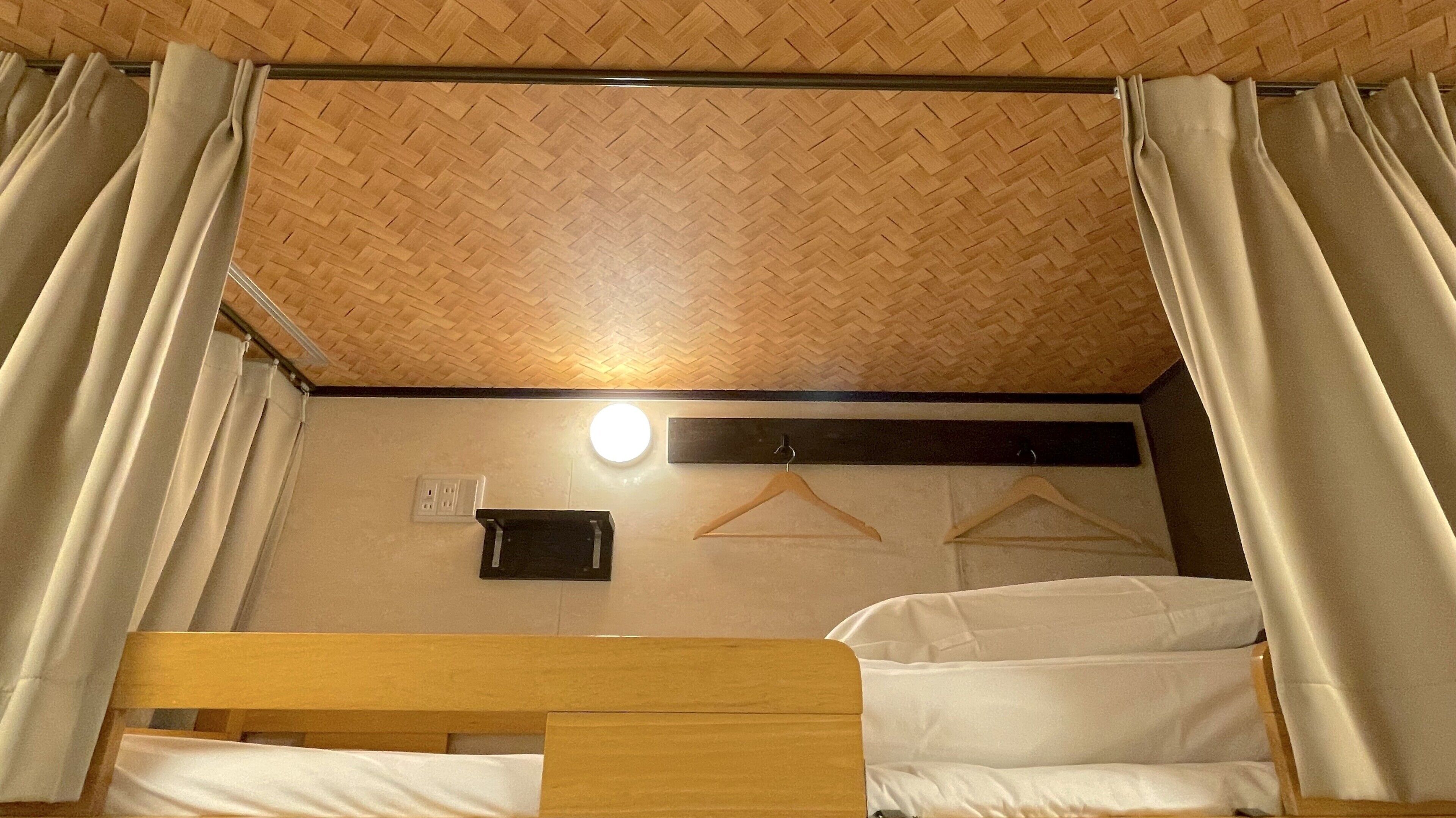 Camera con un letto a castello, soffitto in legno, luce a parete e presa elettrica.