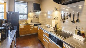 A modern kitchen with wooden cabinets, a stainless steel countertop, and a built-in stove. - Cogo Ryogoku (Tokyo)