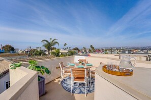 A rooftop terrace with a table set for dining, a water pitcher, and a view of the cityscape.