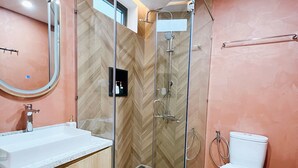 Un baño moderno con ducha acristalada, lavabo blanco y retrete.