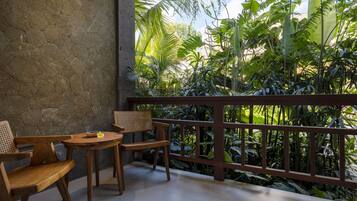 A balcony with wooden furniture and a view of lush tropical plants.