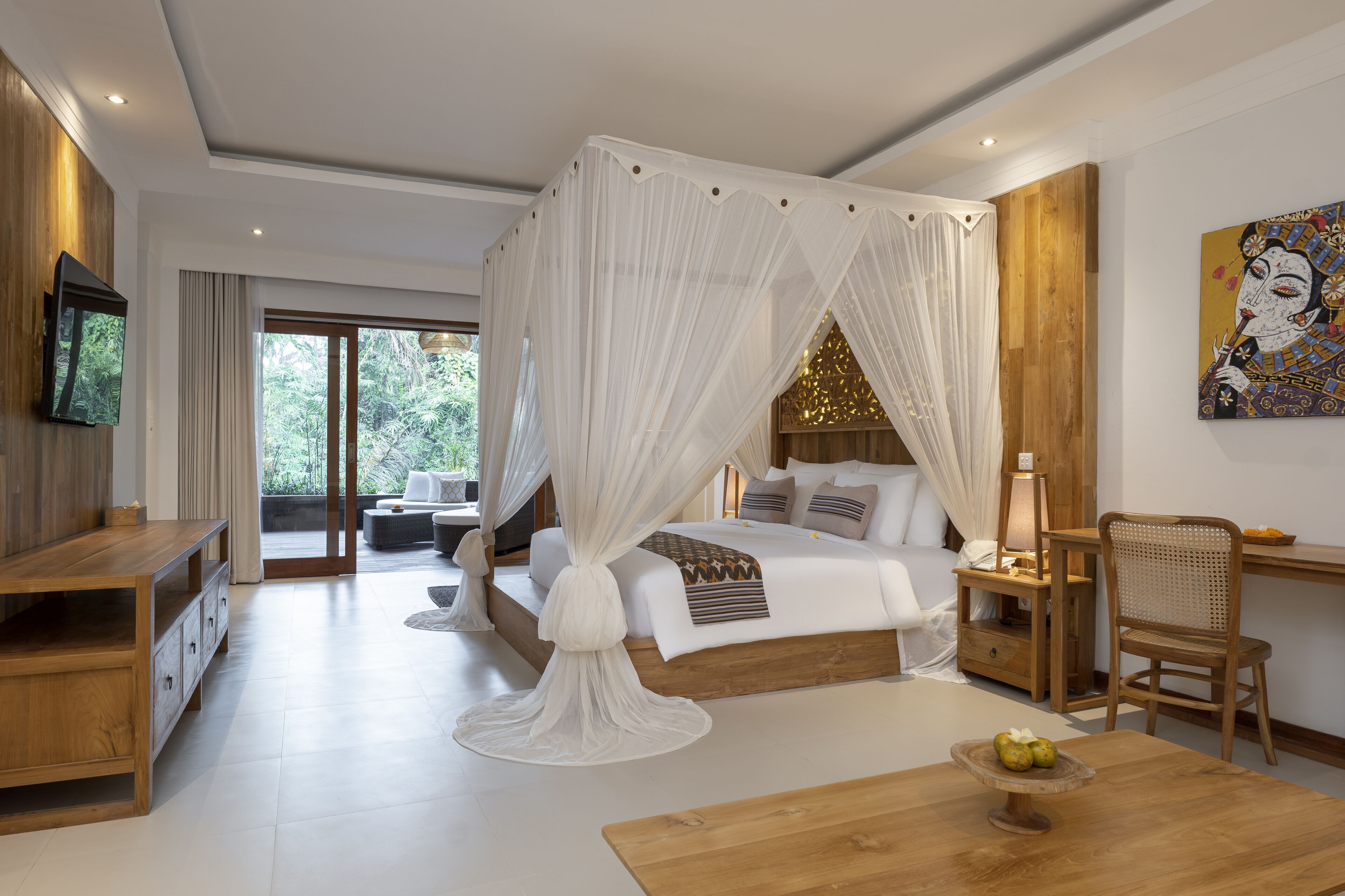 Una camera da letto con un letto a baldacchino, una scrivania in legno, una sedia e un televisore appeso al muro.