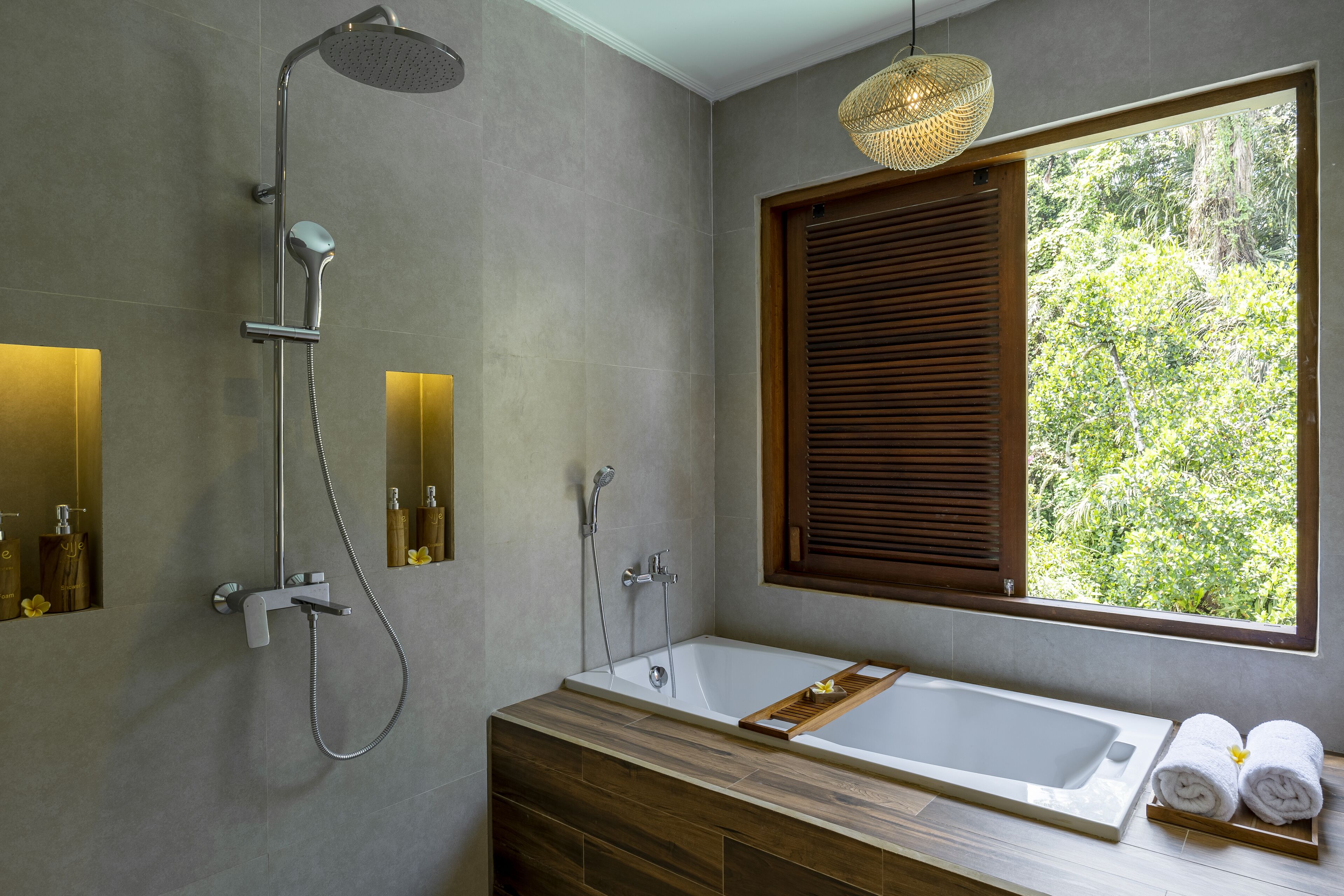 Ein modernes Badezimmer mit einer großen Badewanne, einer Duschbrause und einem Fenster mit Jalousien.