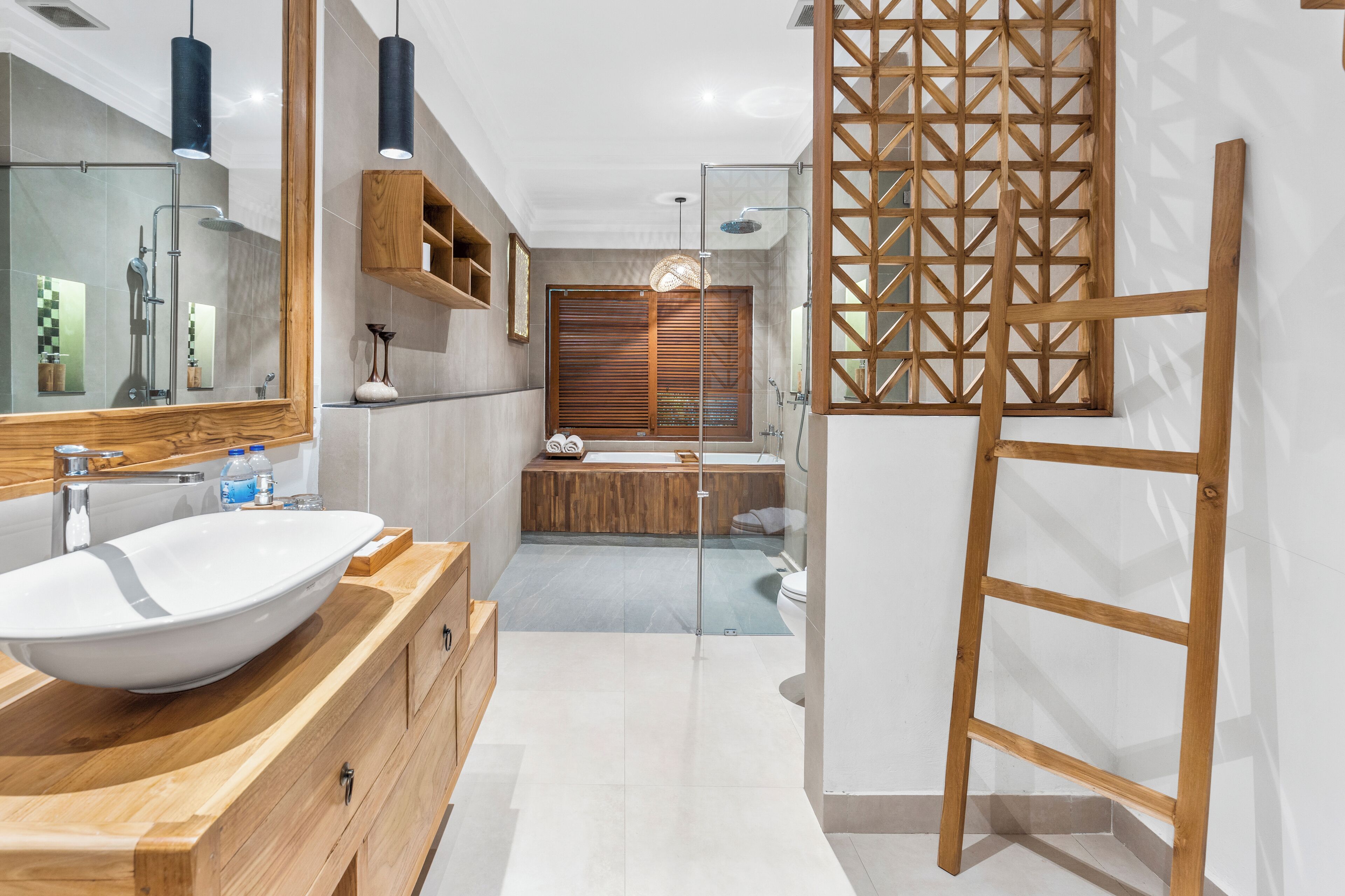 Une salle de bain moderne avec un meuble-lavabo en bois, un grand miroir, une cabine de douche en verre et une échelle en bois adossée au mur.