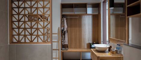 A modern bathroom with a wooden vanity, a large mirror, and a built-in shower area.