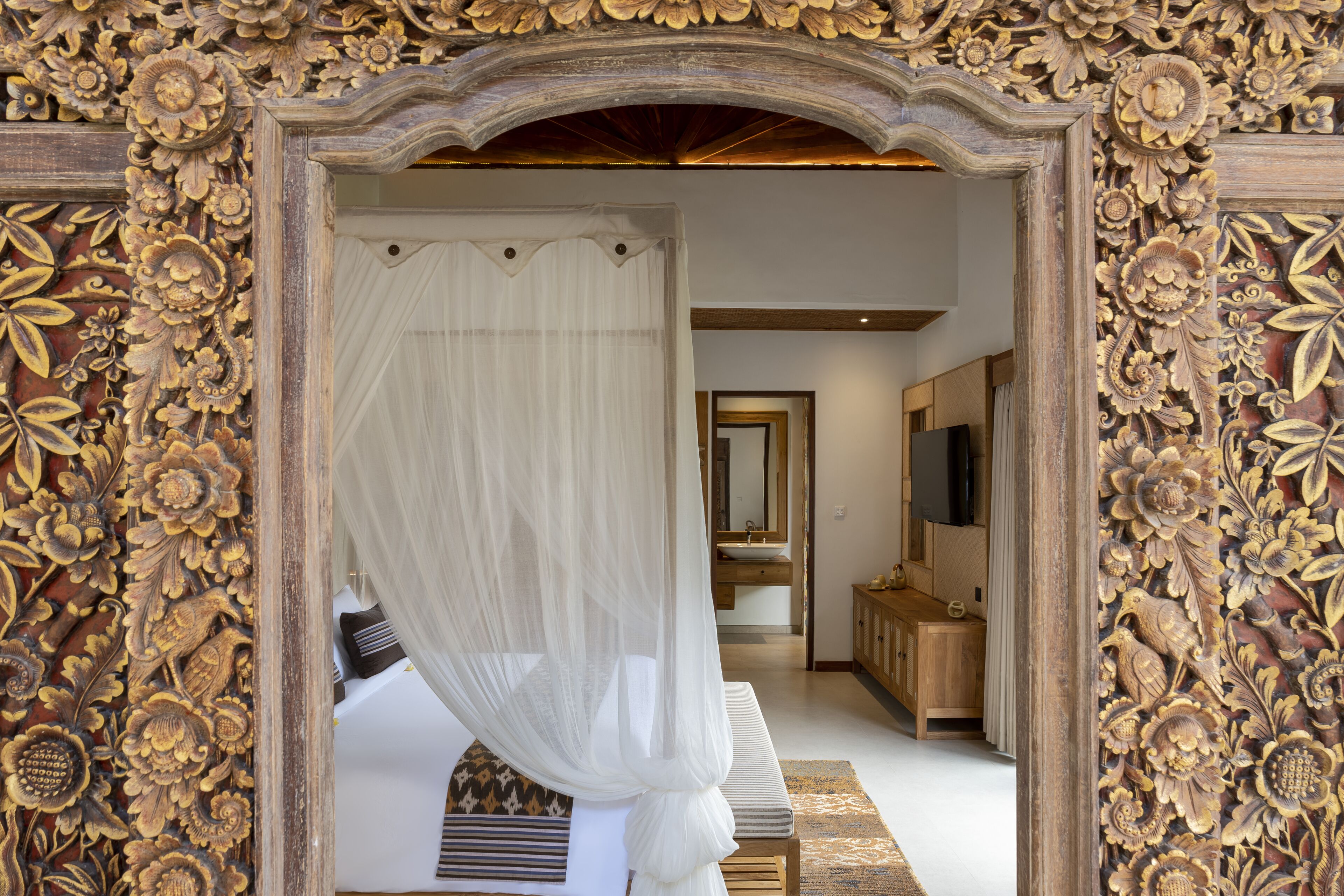 A bedroom with a canopy bed, a wooden headboard, and a large mirror.