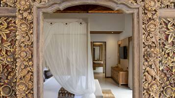 A bedroom with a canopy bed, a wooden headboard, and a large mirror.