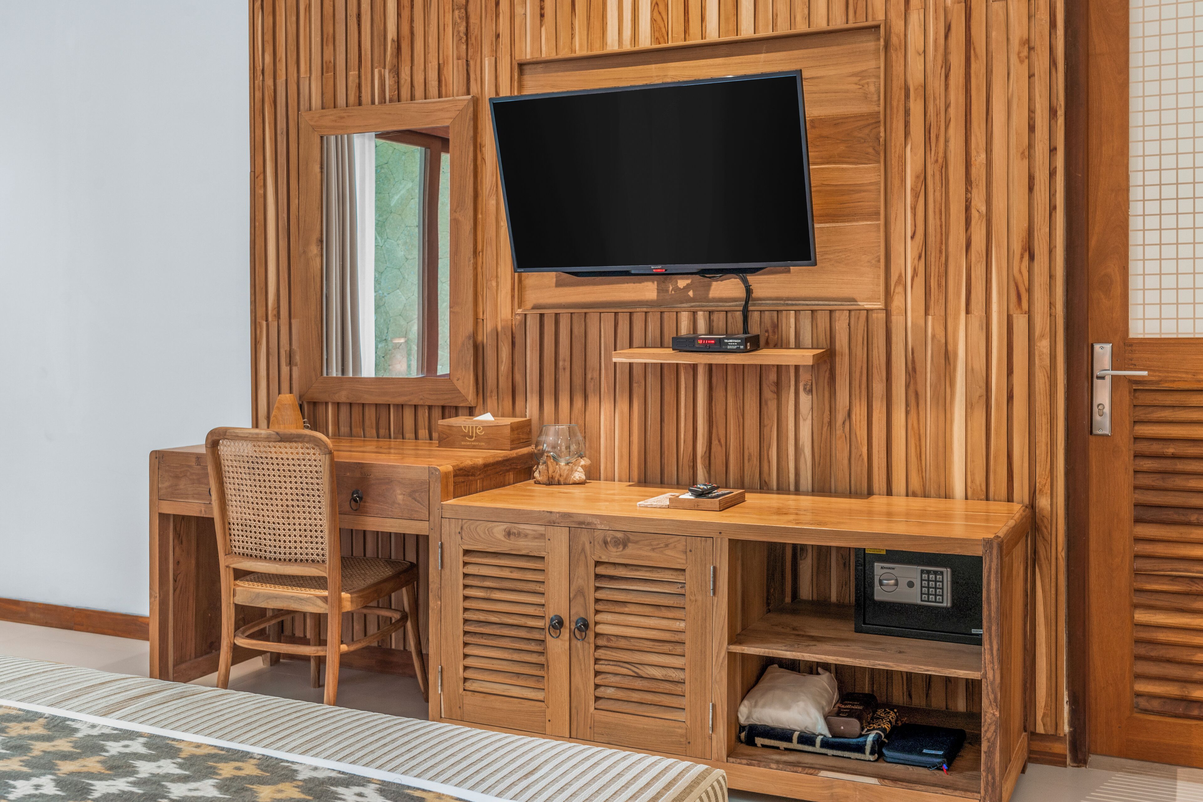 Une pièce en bois contenant un bureau, une chaise, un téléviseur et un coffre-fort.