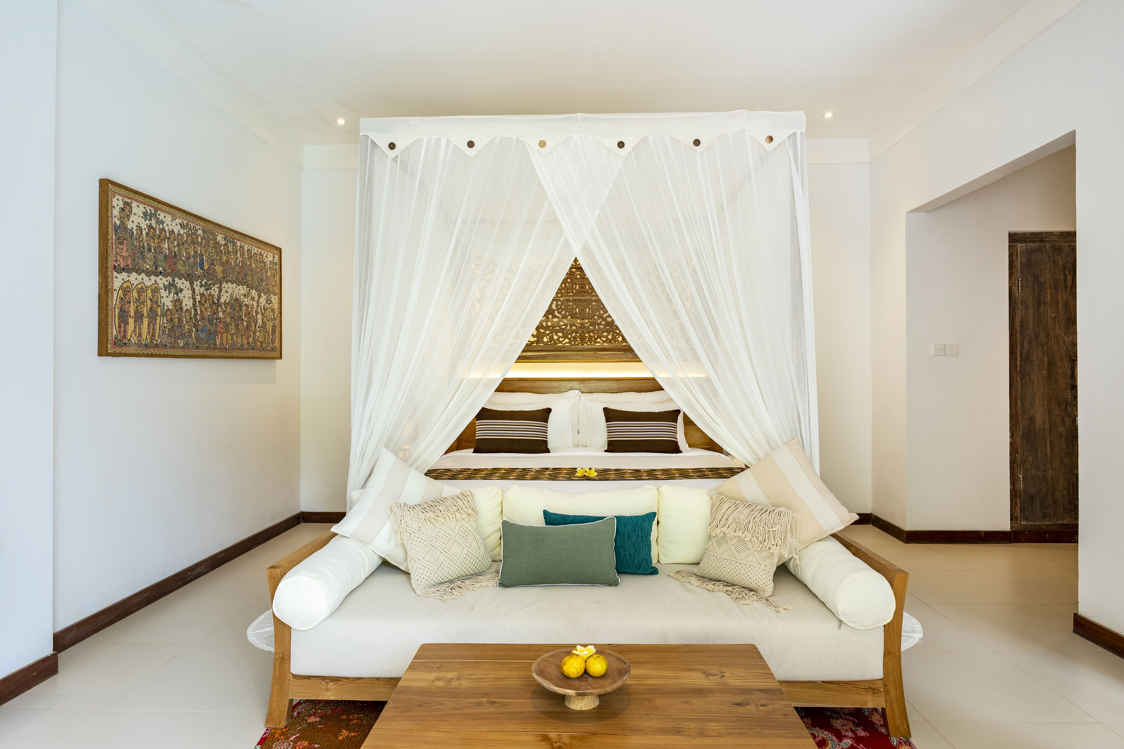 A cozy room with a sofa, a wooden coffee table with fruit, and a decorative wall piece.