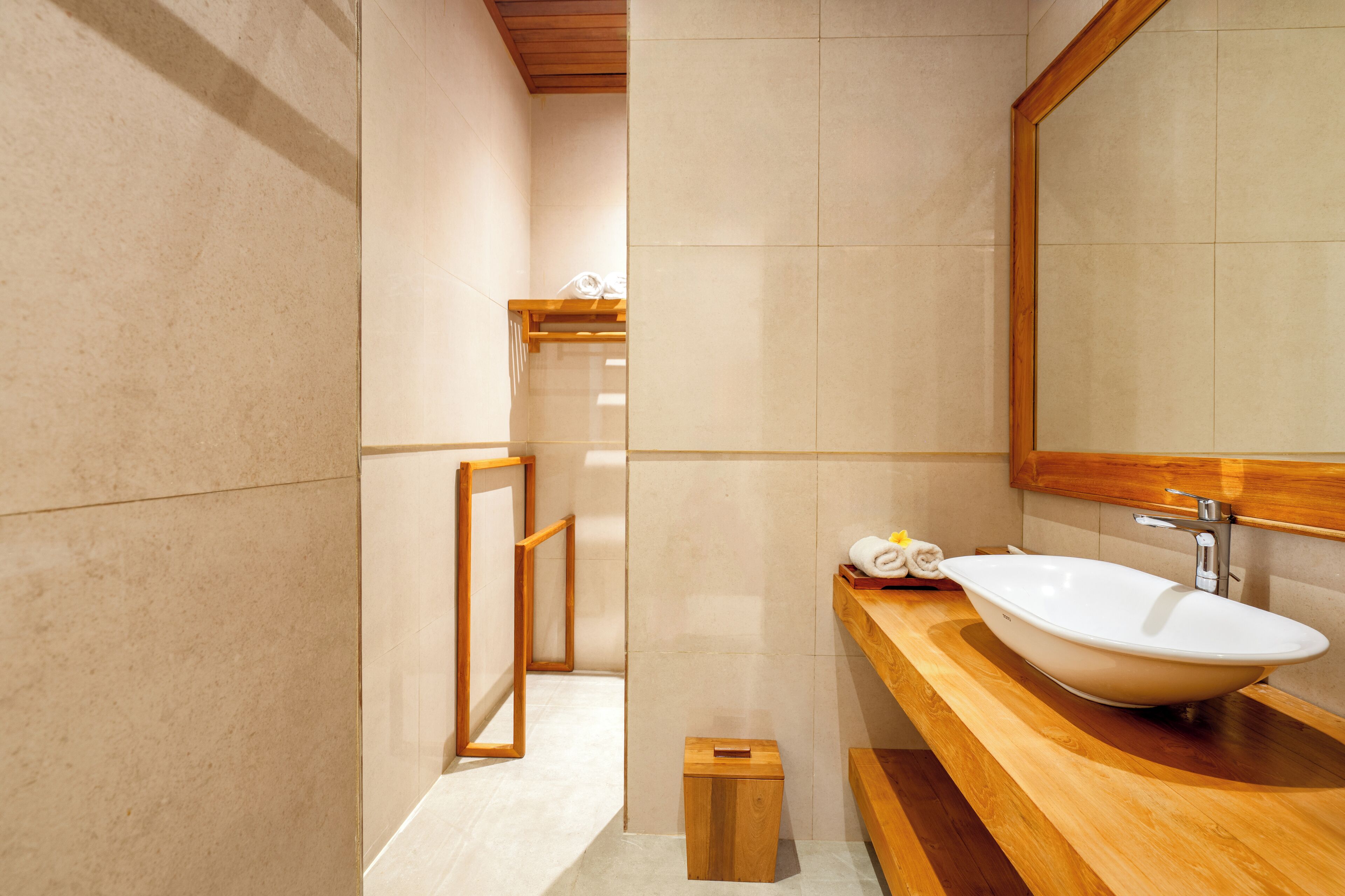 A modern bathroom with a large mirror, wooden vanity, and a freestanding bathtub.