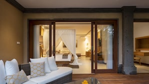 Une chambre d’hôtel moderne, dotée d’un canapé, d ’une table en verre et offrant une vue sur l’intérieur grâce à une porte vitrée.