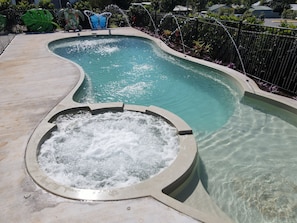 A swimming pool with a hot tub and a decorative butterfly sculpture.