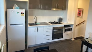 A modern kitchen with white cabinets, a built-in oven, a stove, and a refrigerator. - Peaceful Coombs Apartment for Families (Coombs)