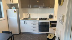 A compact kitchen with a refrigerator, stove, oven, and sink. - Peaceful Coombs Apartment for Families (Coombs)