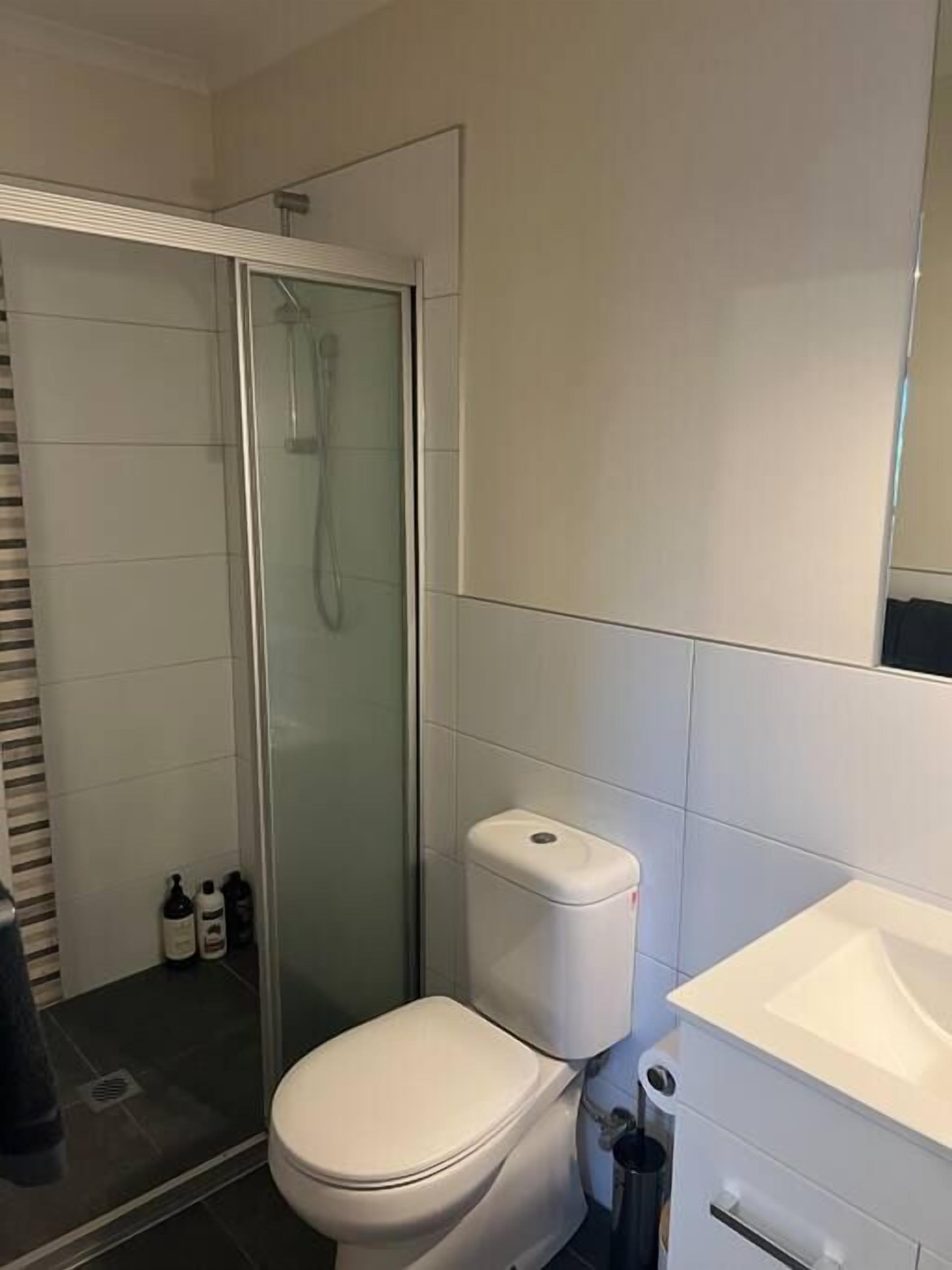 Un bagno moderno con doccia vetrata, water bianco e lavandino bianco.
