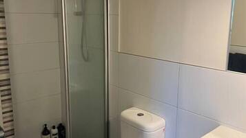 Un bagno moderno con doccia vetrata, water bianco e lavandino bianco.