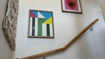 Una escala amb barana de fusta i dos quadres emmarcados a la paret.