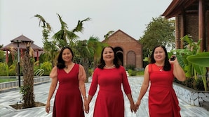 Tres mujeres con vestidos rojos caminando por un sendero de mármol.