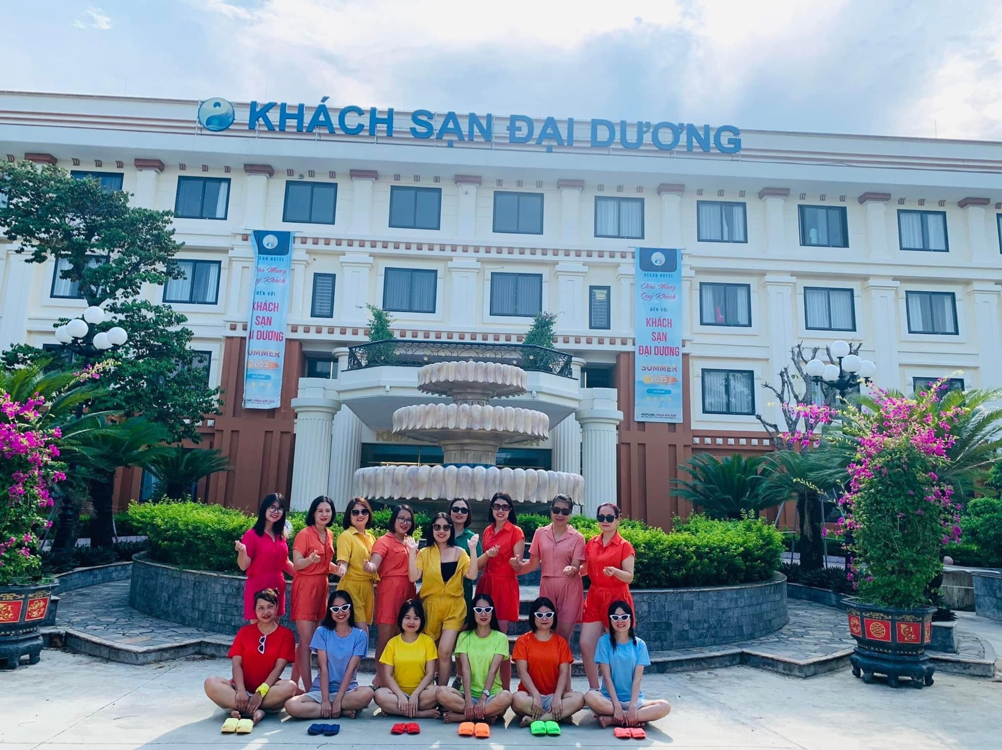 A hotel with a large entrance, a fountain, and banners advertising summer 2022.