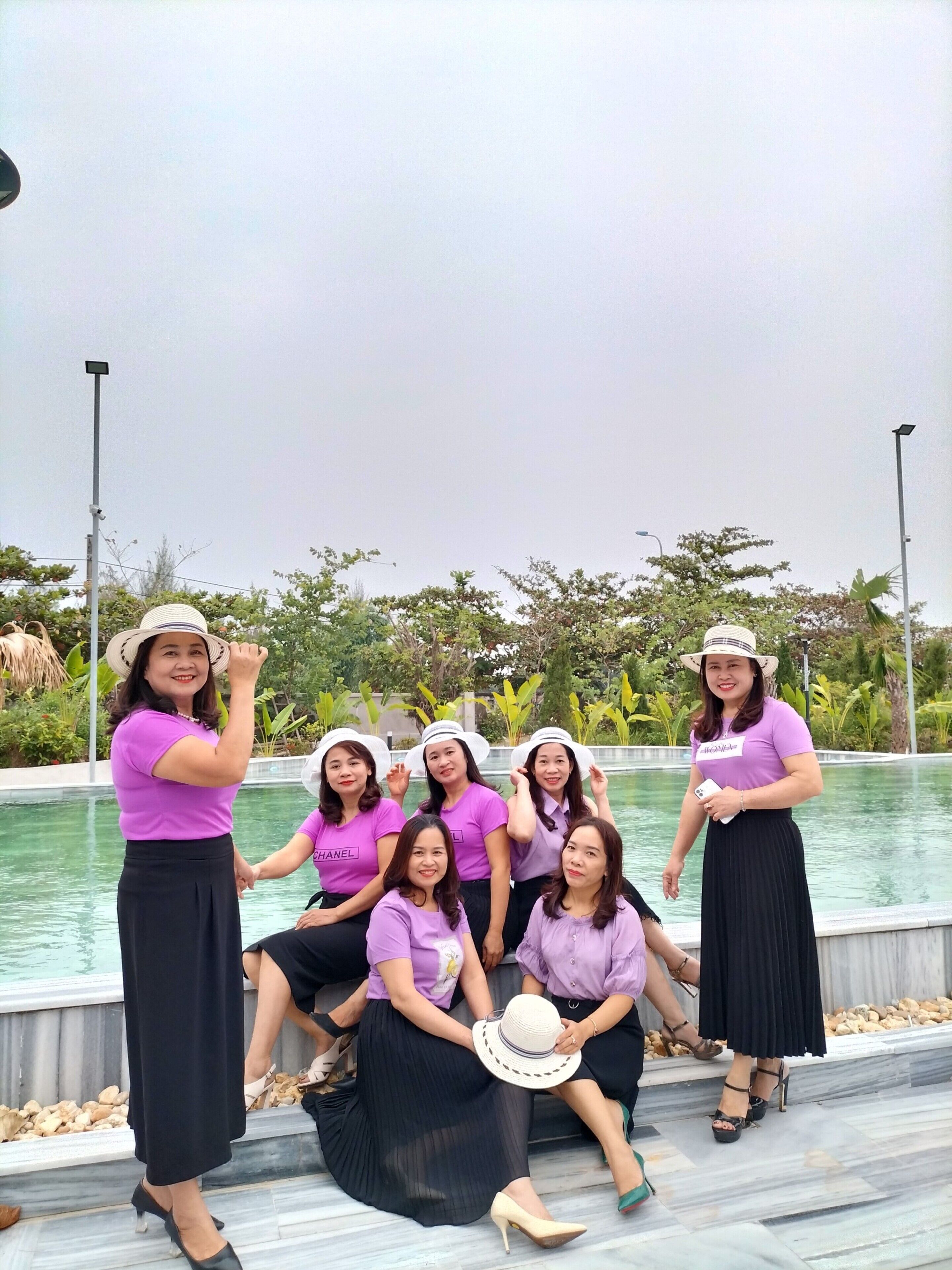 Un grupo de personas posando junto a una piscina, con vistas claras al agua y la vegetación circundante.