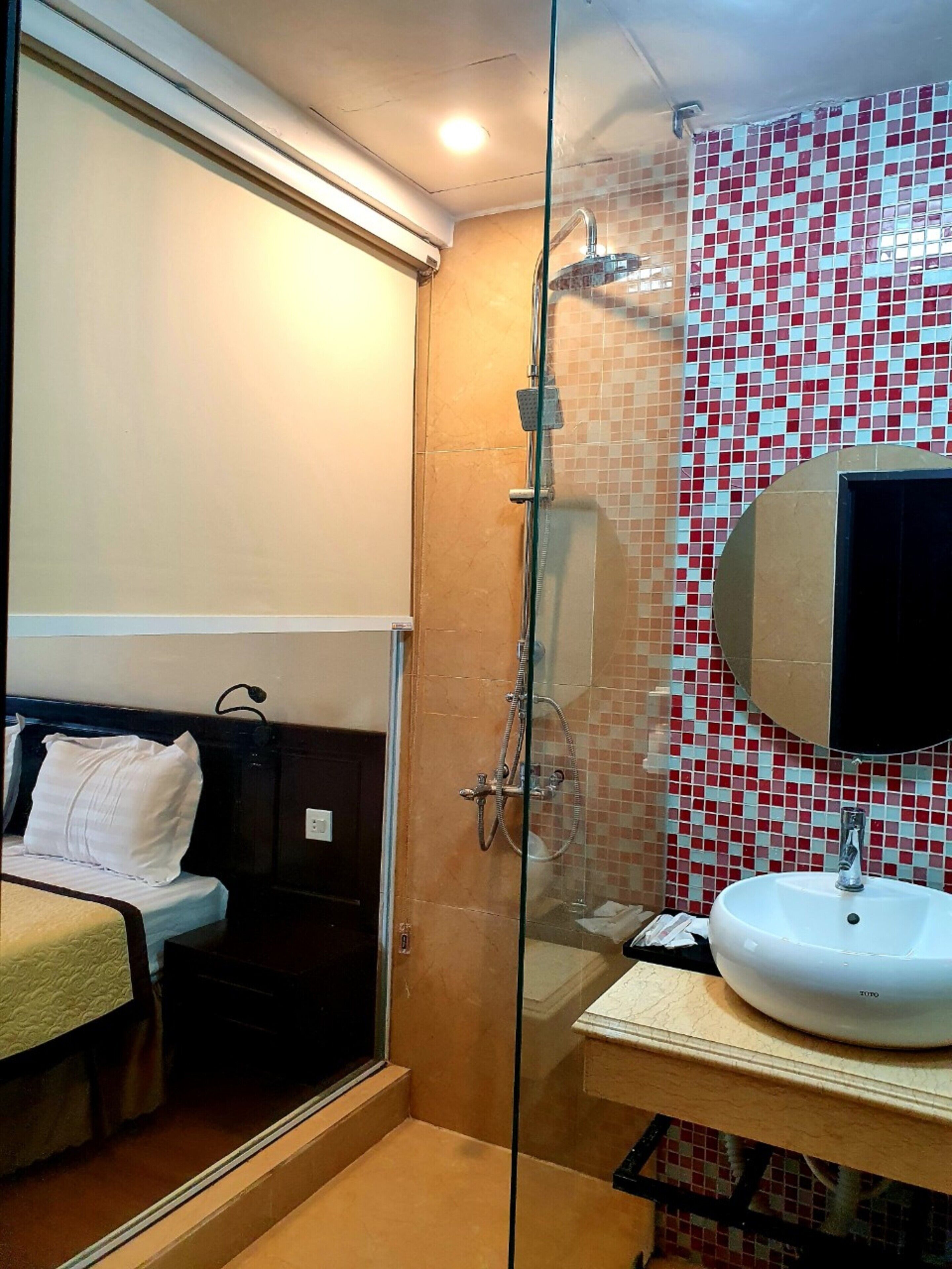 Un baño con cabina de ducha de vidrio, un lavamanos blanco y pared con azulejos.